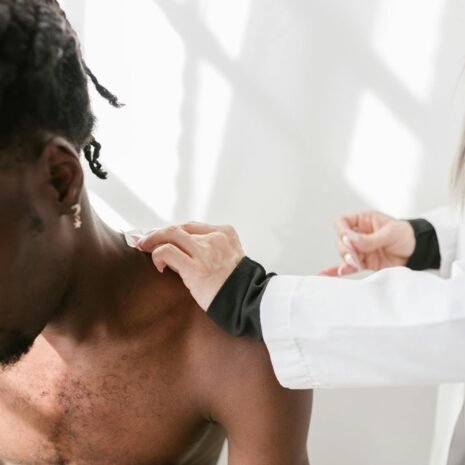 Close-up of a man receiving a shoulder massage for pain relief indoors.
