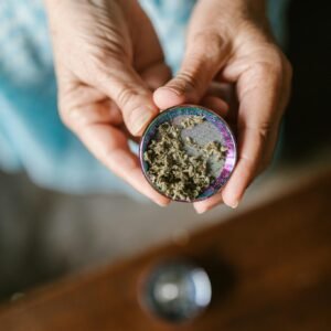Close-up of hands holding a cannabis grinder filled with marijuana. Ideal for cannabis culture visuals.