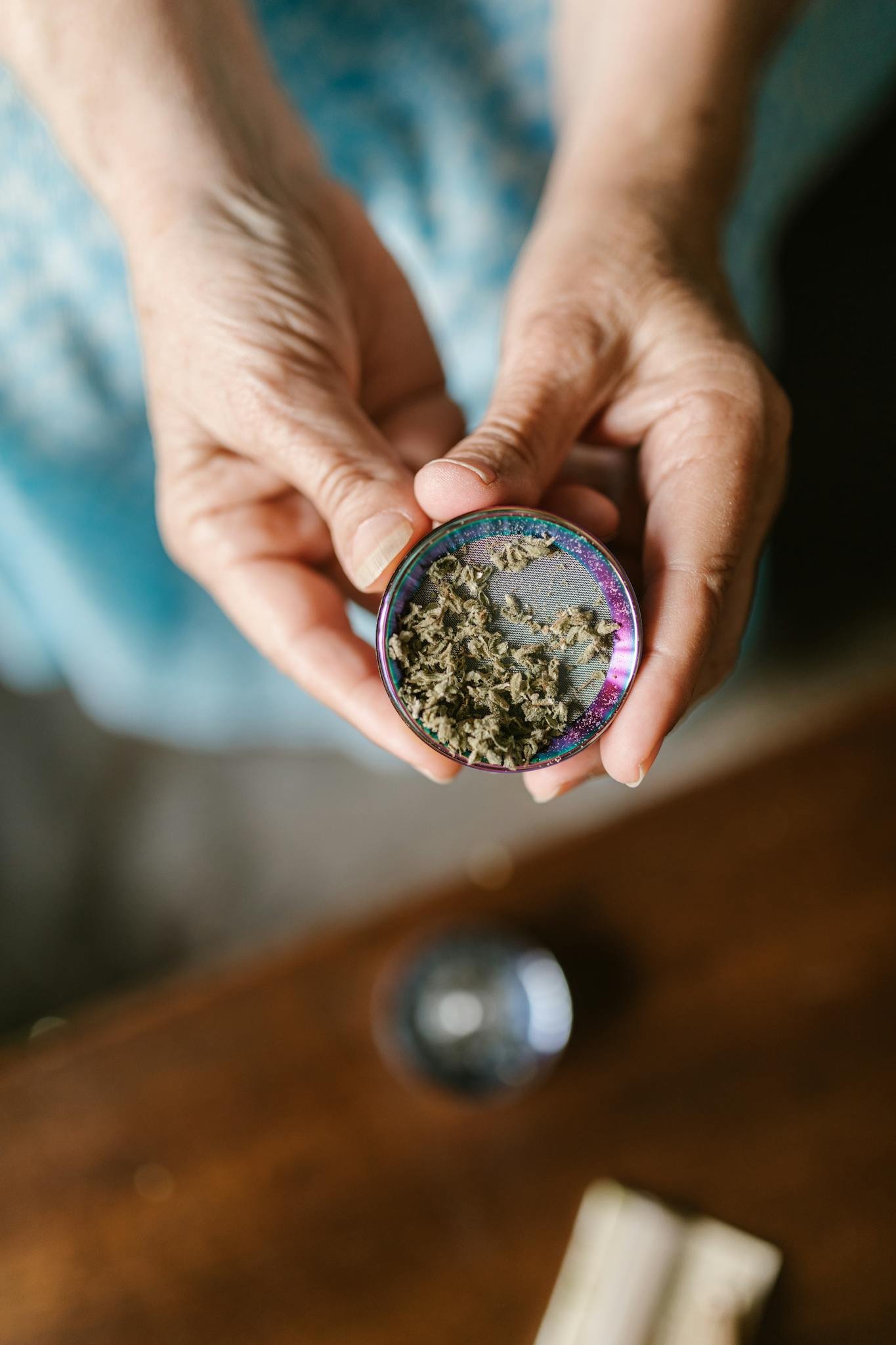 Close-up of hands holding a cannabis grinder filled with marijuana. Ideal for cannabis culture visuals.